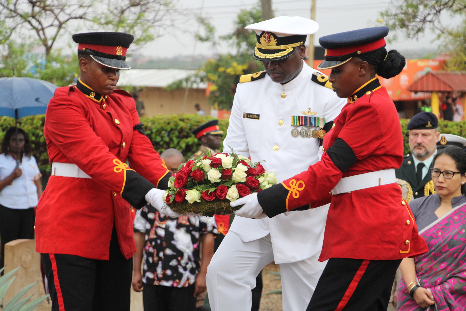 The Deputy Commander of the Kenya Navy, Brigadier John Kiswaa (in white) holding a bouquet of flowers ready to place it at the World War I cemetery in Voi.