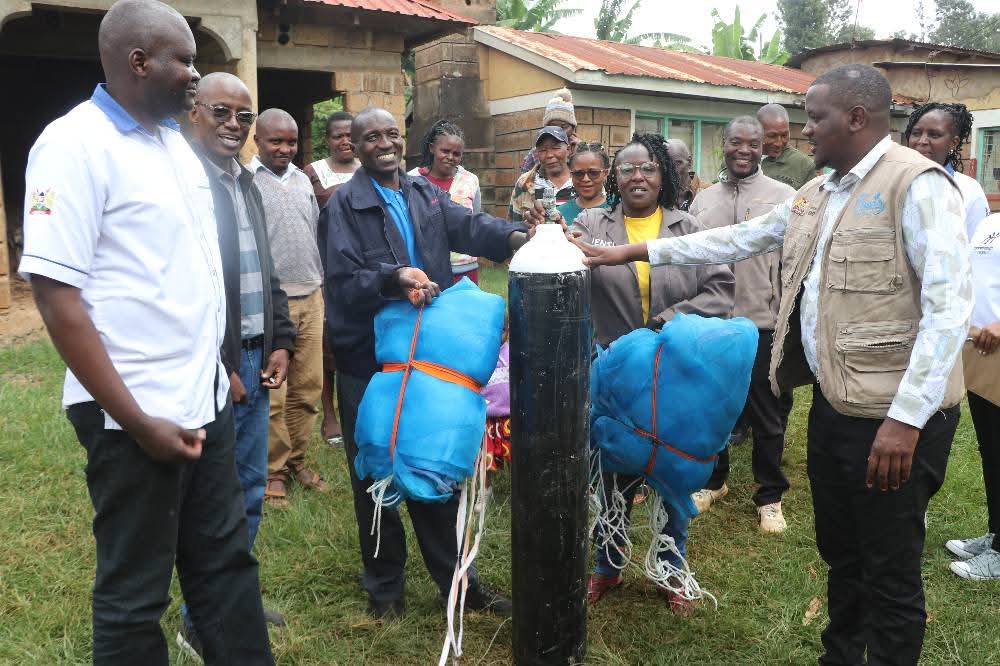 Tharaka Nithi County Fisheries Chief Officer Antony Kiruja issues an oxygen cylinder to farmers' at Kamwimbi. Photo/Dickson Mwiti)