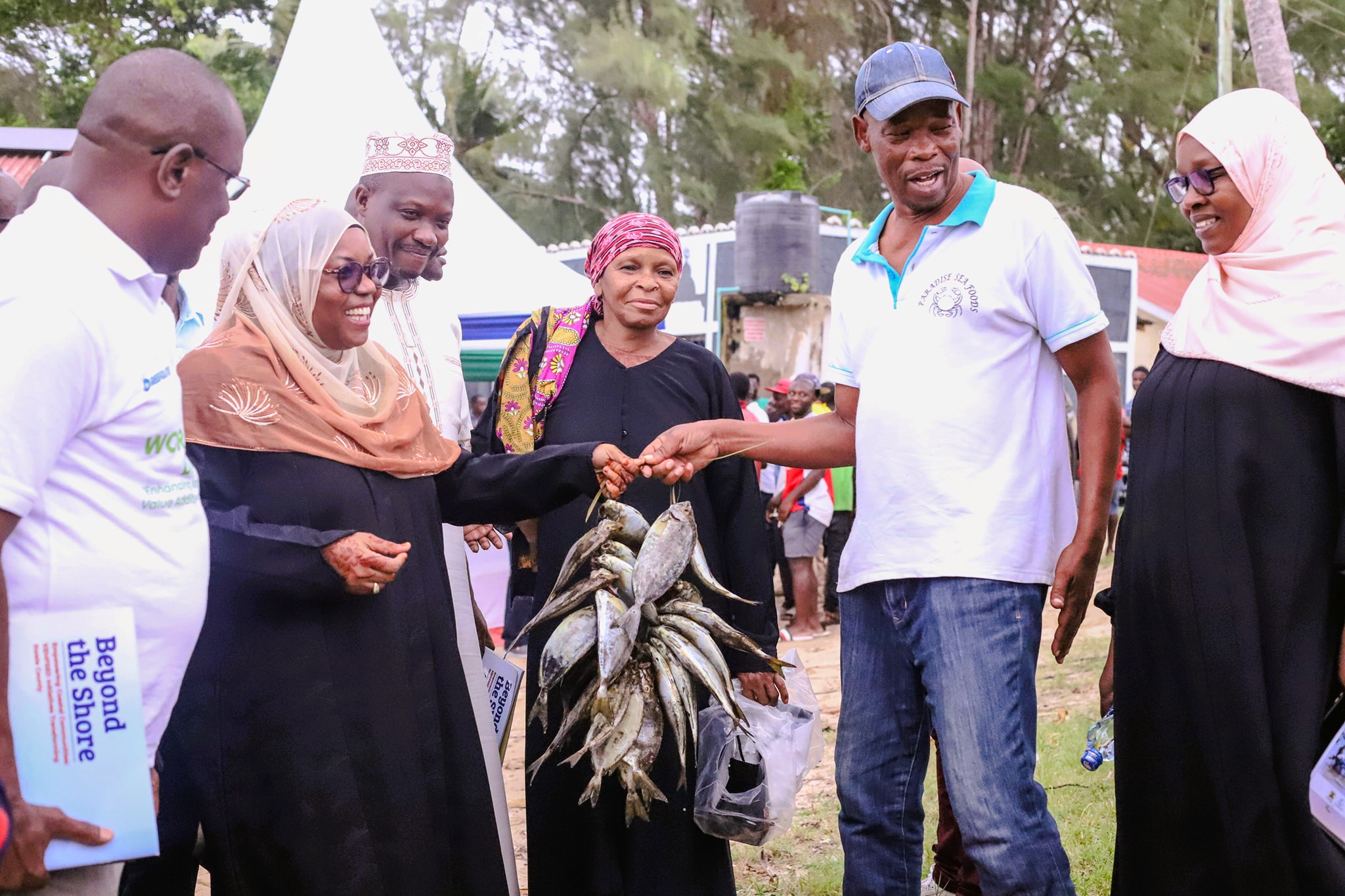 Kwale Governor Fatuma Achani (2nd L) admires fish caught by local fishermen in Msambweni sub county during the distribution of essential fishing equipment to local fisherfolk