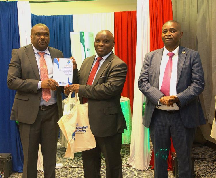 Industrialization Secretary Prof. Erastus Gatebe officially hands over the Report on the Second International Symposium on Intellectual Property Protection and Enforcement ISIPPE-2 to the Executive Director, Anti-Counterfeit Authority Dr. Robi Mbugua Njoroge. Photo/