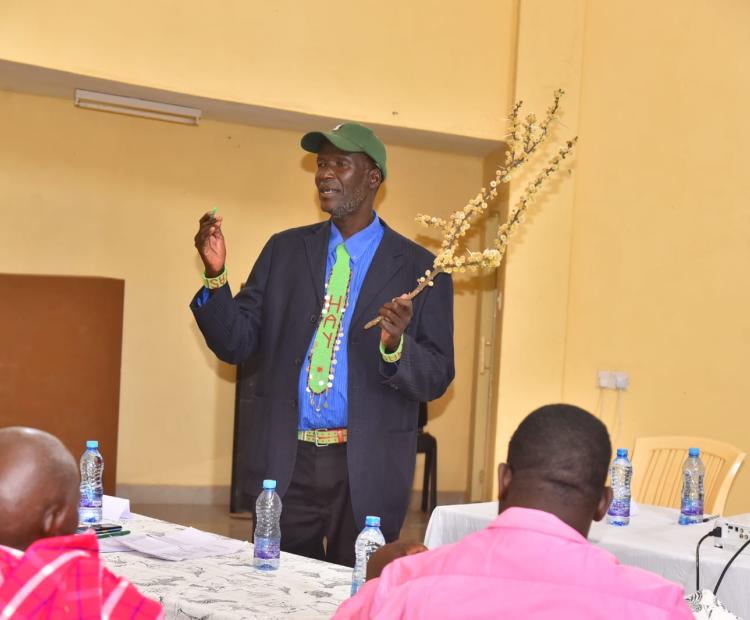 Mzee John ole Wuapari, one of the traditional experts on weather forecasting explains how they forecast the weather using the flowering of plants. Photo/Diana Meneto.